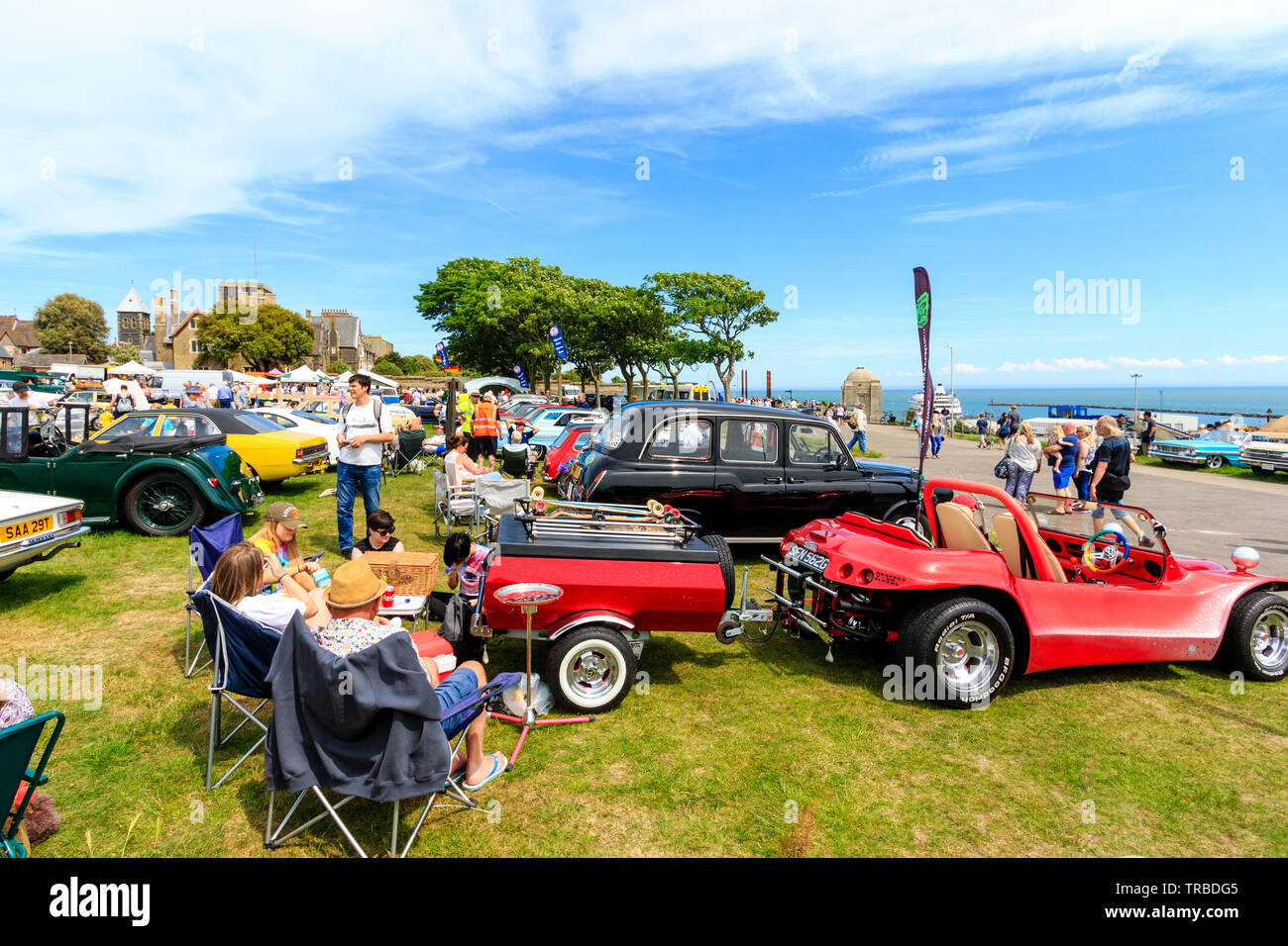 Das 38. Jahr der jährliche Schaufel und Spaten Classic Car Run von Canterbury nach Ramsgate Strandpromenade. Klassische Autos, alte und moderne, in Reihen auf dem Rasen geparkt mit Menschen zu Fuß rund um Ihre Anzeige auf hellen, sonnigen Tag. Stockfoto