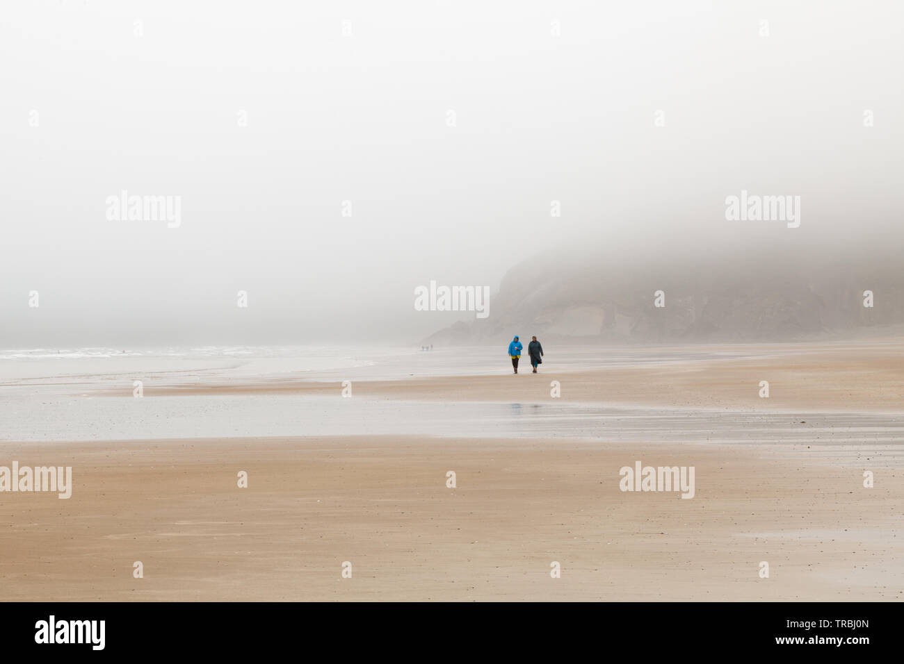 Newgale Strand in Pembrokshire auf einem grauen, nebligen Tag. 2 Frauen zu Fuß am Strand entlang Stockfoto