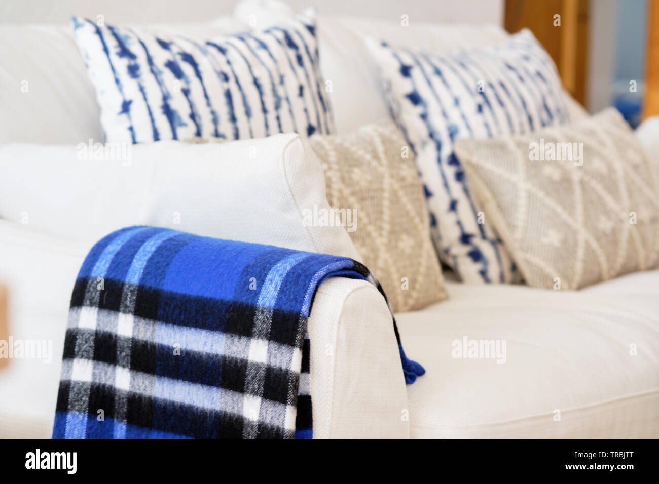 Wohnzimmer Einrichtung mit Stoff Material Farbe weiß Sofa blau beige Elemente Kissen und plaid Nahaufnahme Bild keine Personen, Moderne gemütliche Wohnung Stockfoto