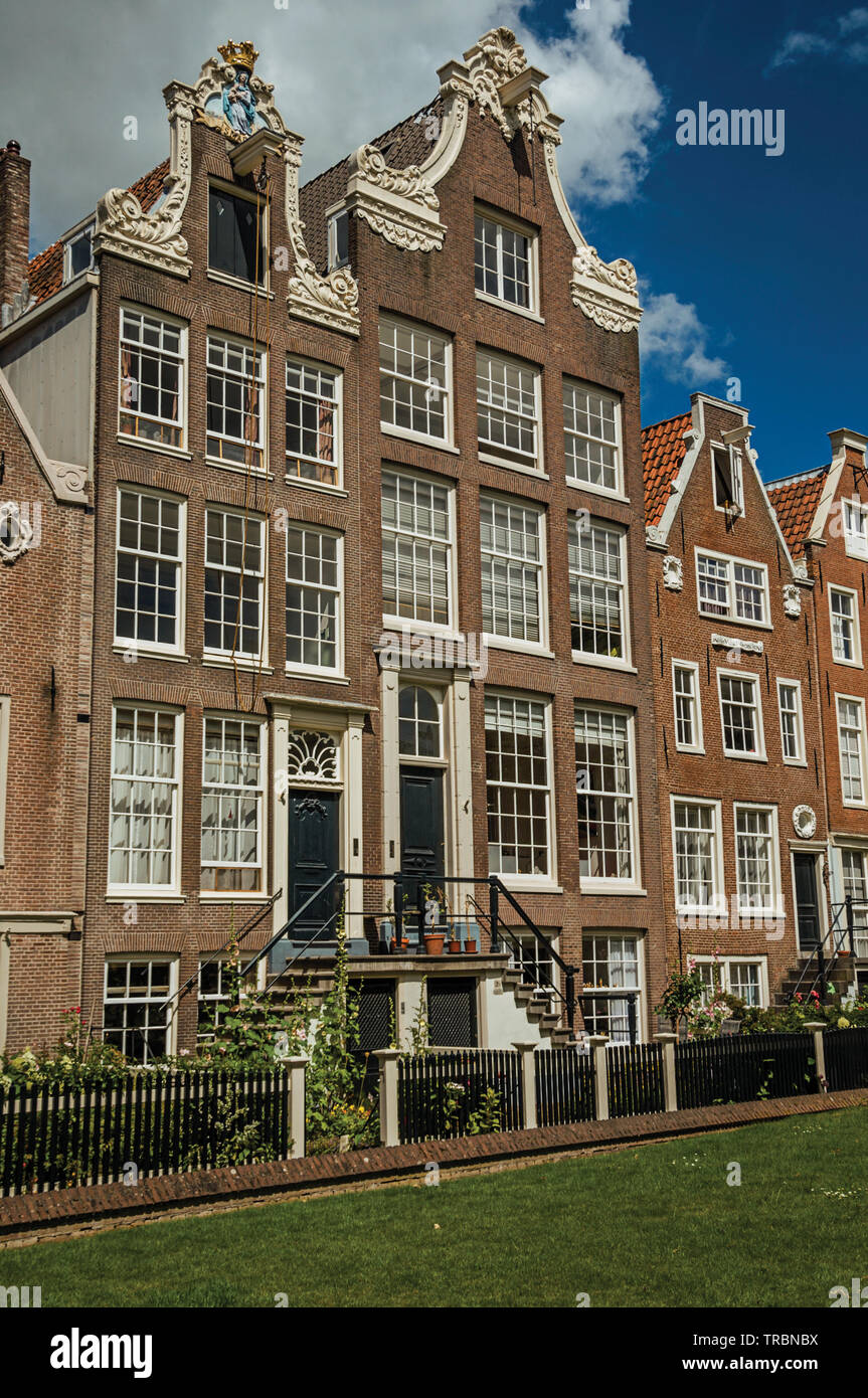 Typische Häuser und grünen Garten des Begijnhof, einem mittelalterlichen Gemeinschaft in Amsterdam. Stadt mit riesigen kulturelle Aktivität, Kanäle und Brücken in den Niederlanden. Stockfoto