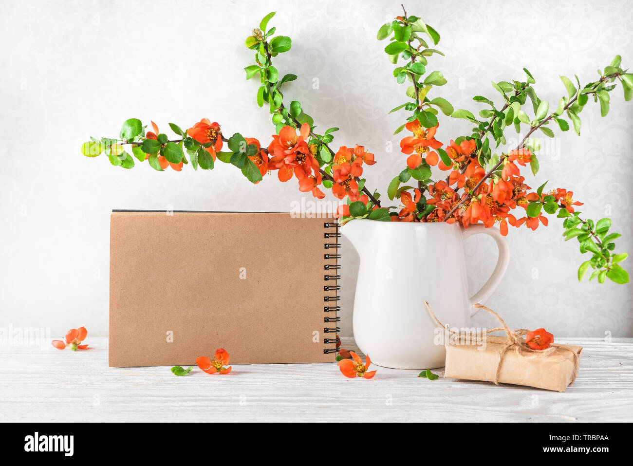 Noch immer leben mit einem wunderschönen Frühling orange Blumen, Tasse Tee und leeres Papier notebook auf weißer Tisch. Mock up. Urlaub oder Hochzeit Hintergrund Stockfoto