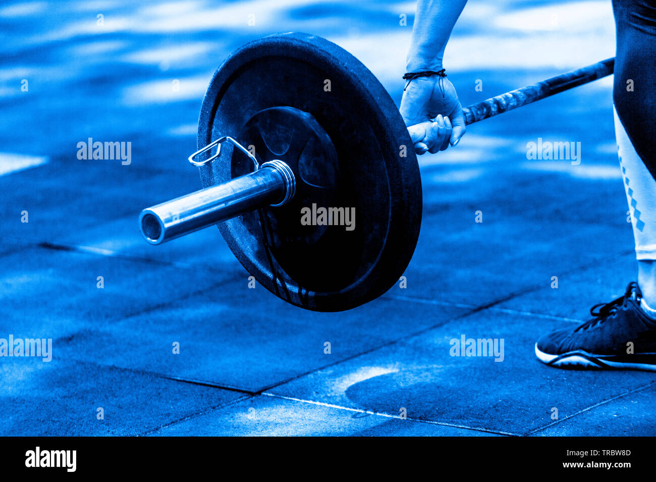 Crossfit Frau vorbereiten für Ihre weightlifting Workout mit einem schweren Hantel. Blaue Farbe Stockfoto