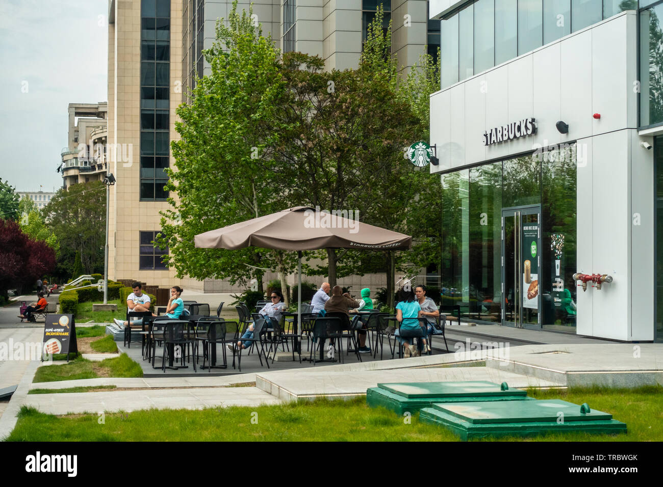 Kunden entspannen in der Terrasse mit Sitzgelegenheiten außerhalb einer Filiale von Starbucks im Zentrum von Bukarest/Rumänien București Stockfoto