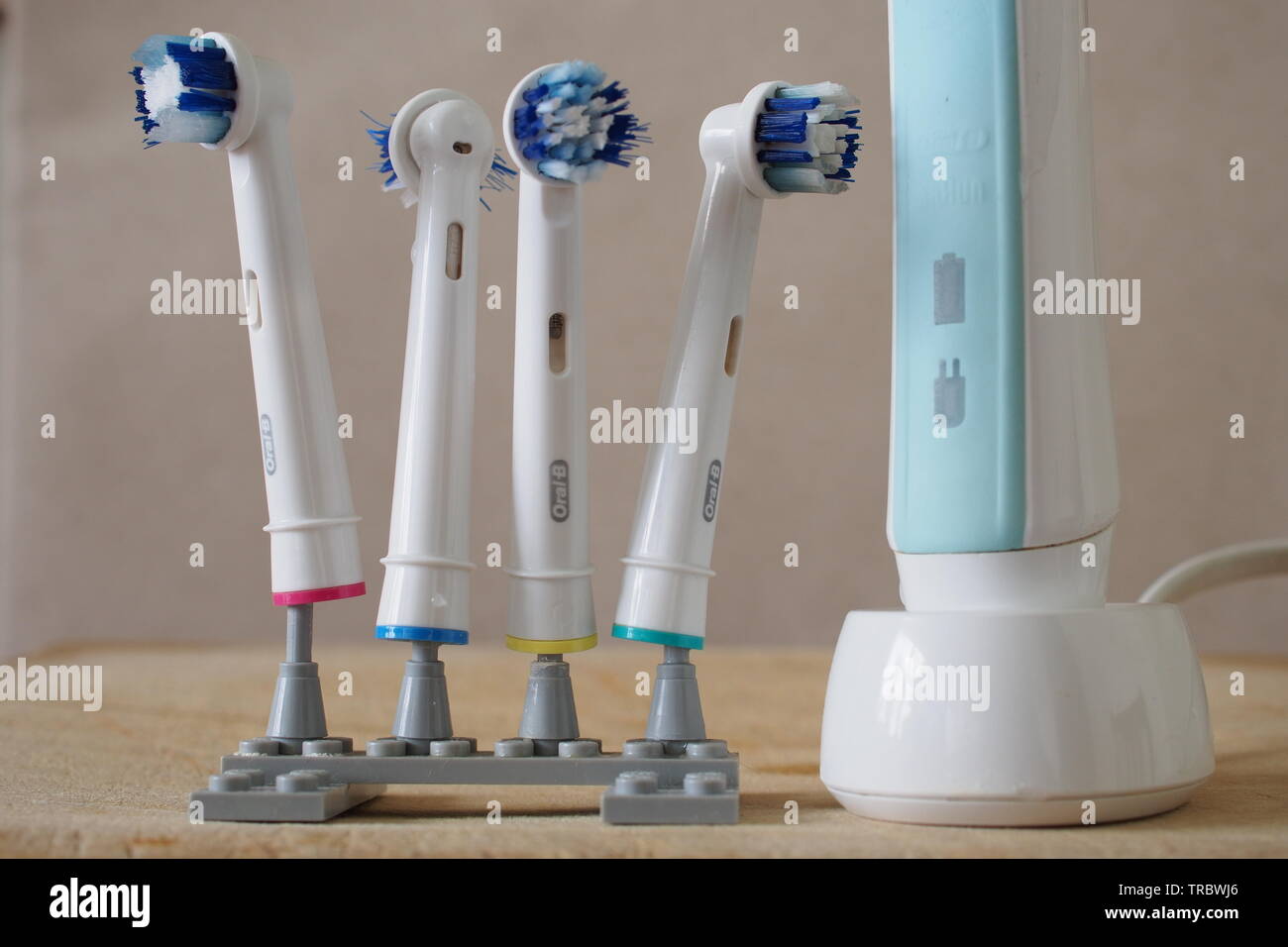 Vier gut verwendet elektrische Zahnbürste Köpfe auf ein Lego stand, neben  einem Braun elektrische Zahnbürste auf die Drahtlose wiederaufladbare Base  Stockfotografie - Alamy