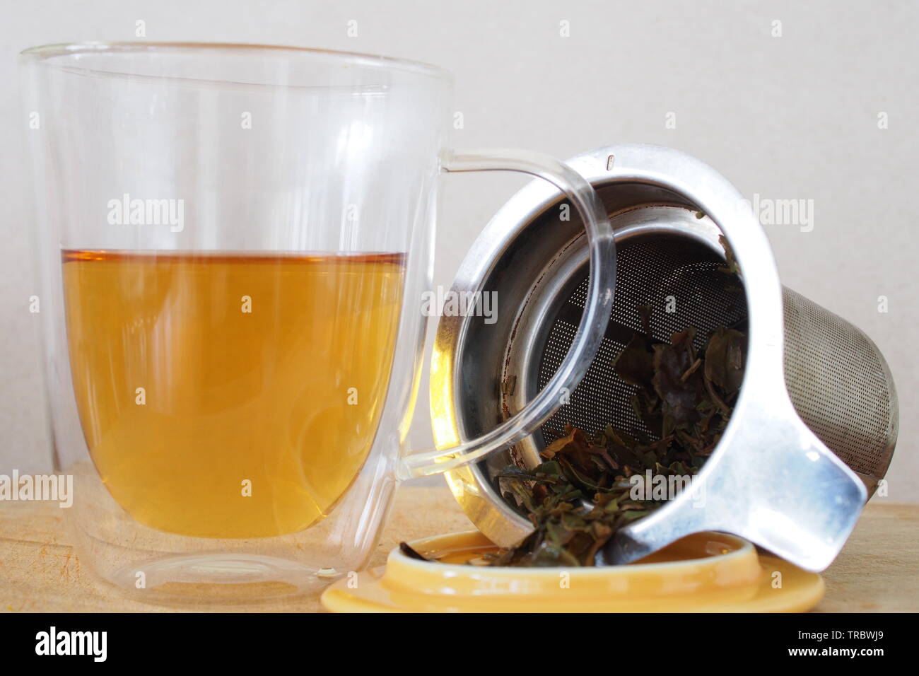 Voller grüner Tee in einem Glas Schale neben einem Edelstahl Sieb und Deckel. Tatsächlich Darjeeling first flush verhält und wie ein grüner Tee. Stockfoto