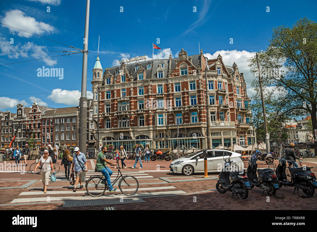 Straße mit typischen Backsteinbauten, Menschen und Radfahrer vorbei in Amsterdam. Stadt mit riesigen kulturelle Aktivität, Kanäle und Brücken in den Niederlanden. Stockfoto