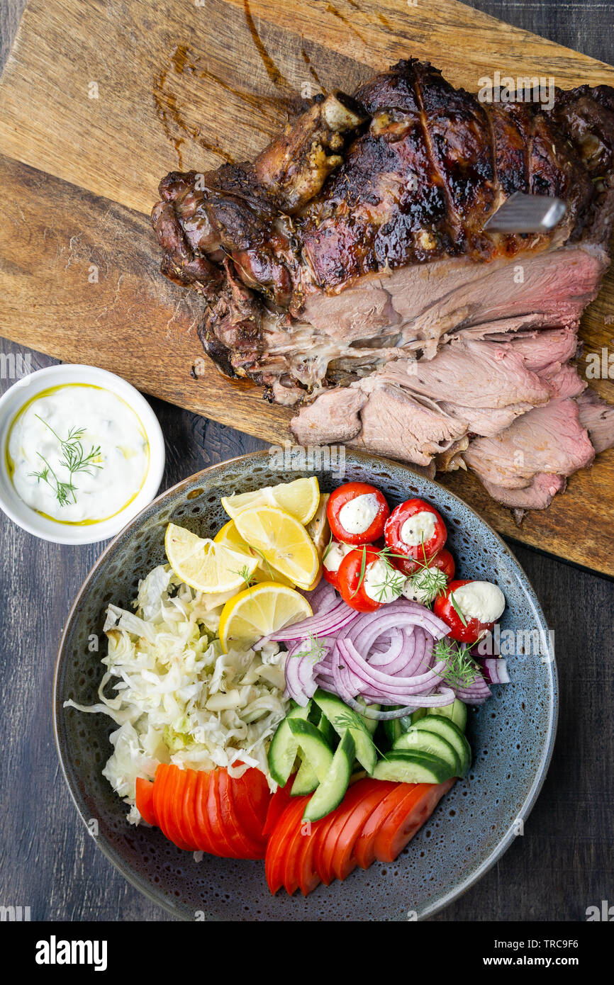 Lecker Lamm bein Braten auf eine Rotisserie mit frischen griechischen Salat und Soße für Souvlaki wraps serviert gekocht. Stockfoto
