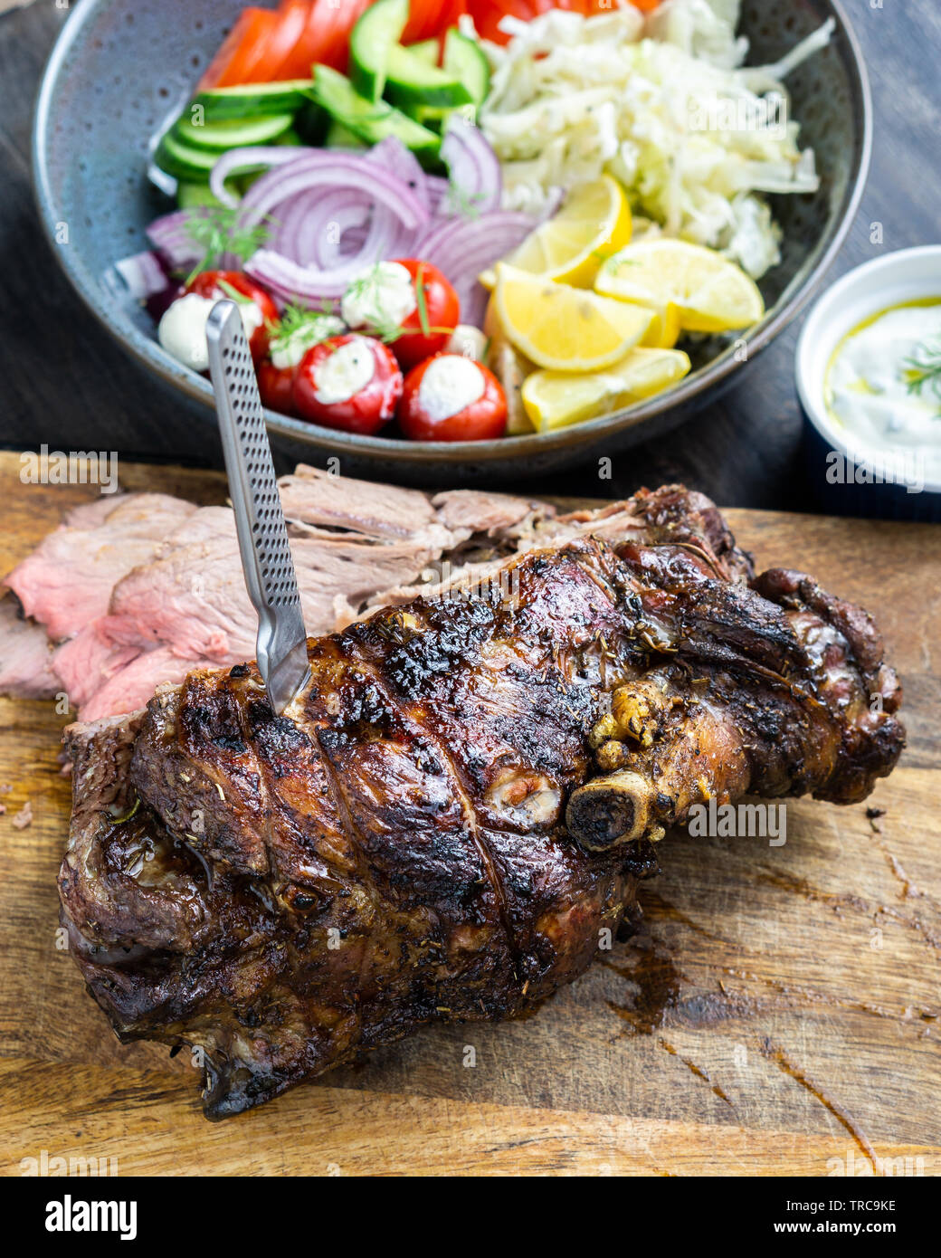Lecker Lamm bein Braten auf eine Rotisserie mit frischen griechischen Salat und Soße für Souvlaki wraps serviert gekocht. Stockfoto