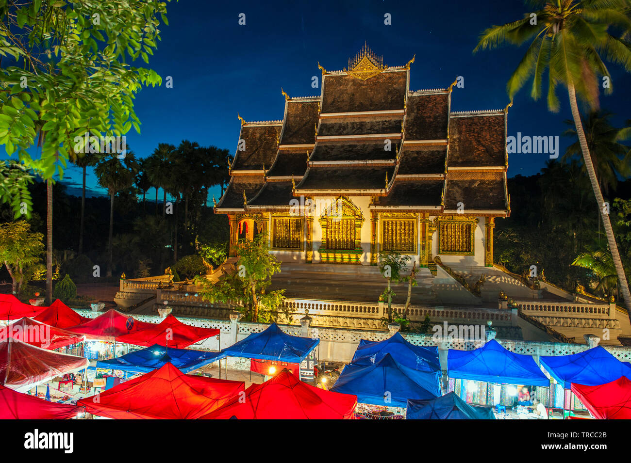 Die Hmong Nachtmarkt mit Haw Pha Bang Tempel im Hintergrund im Zentrum von Luang Prabang, ein Weltkulturerbe Stadt in Laos aufgeführt. Stockfoto