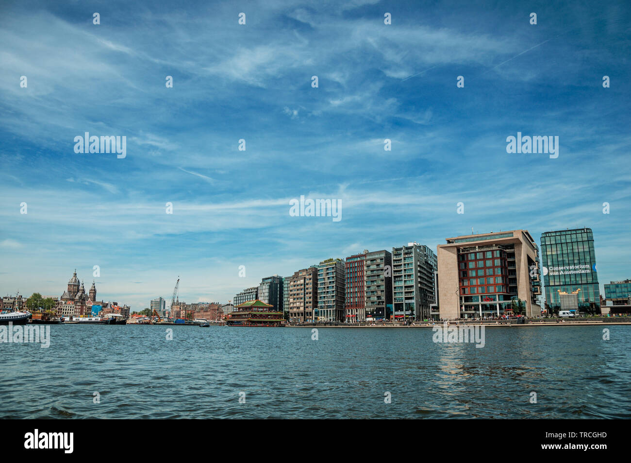 Port, Kirchtürme und modernen Gebäuden auf Canal Bank und blauer Himmel in Amsterdam. Stadt mit riesigen kulturelle Aktivität, Kanäle und Brücken in den Niederlanden. Stockfoto