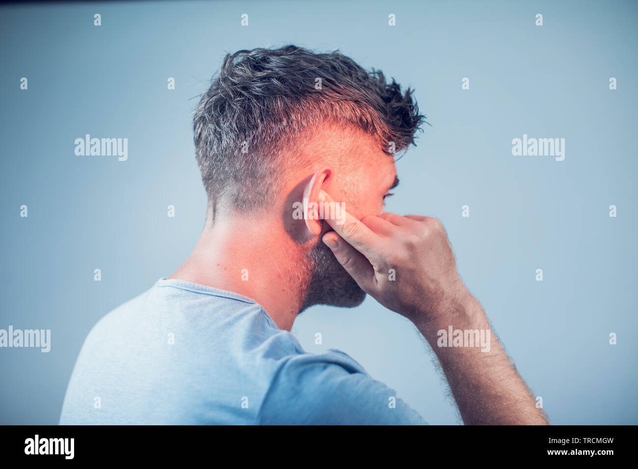 Männliche in Ohrenschmerzen berühren seine schmerzhaften Kopf auf grauem Hintergrund Stockfoto