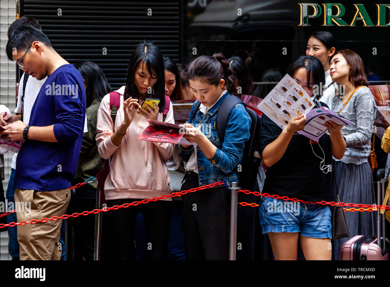 Wohlhabende junge Menschen in Hongkong Warteschlange außerhalb ein Shop in Causeway Bay, Hong Kong, China Stockfoto