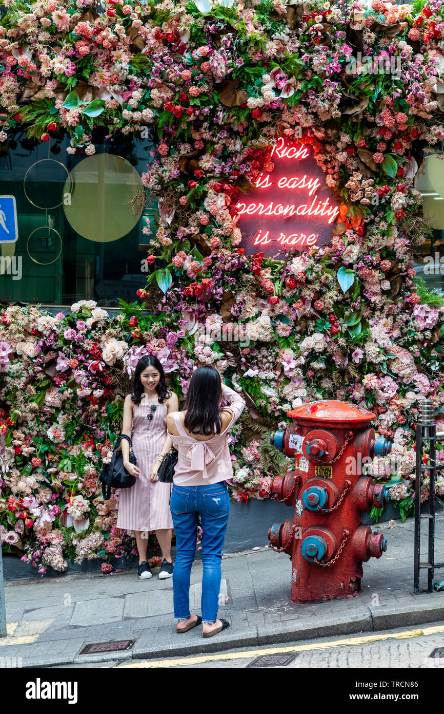 Eine Frau stellt für Fotos durch einen vertikalen Garten, Hongkong, China Stockfoto