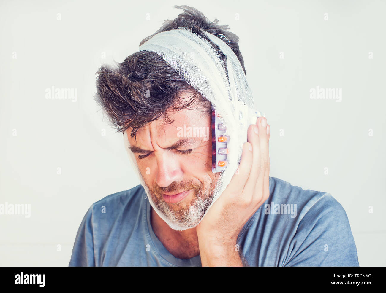 Der Mensch in der medizinischen Bandage und Pillen auf grauem Hintergrund Stockfoto