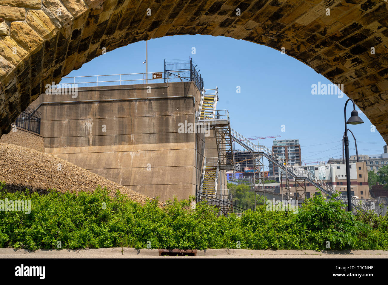 Minneapolis, MN - Juni 2, 2019: Steinbogenbrücke Frames der St. Anthony Falls Sperren und Damm auf dem Mississippi Fluss in der Innenstadt von Minneapolis Stockfoto