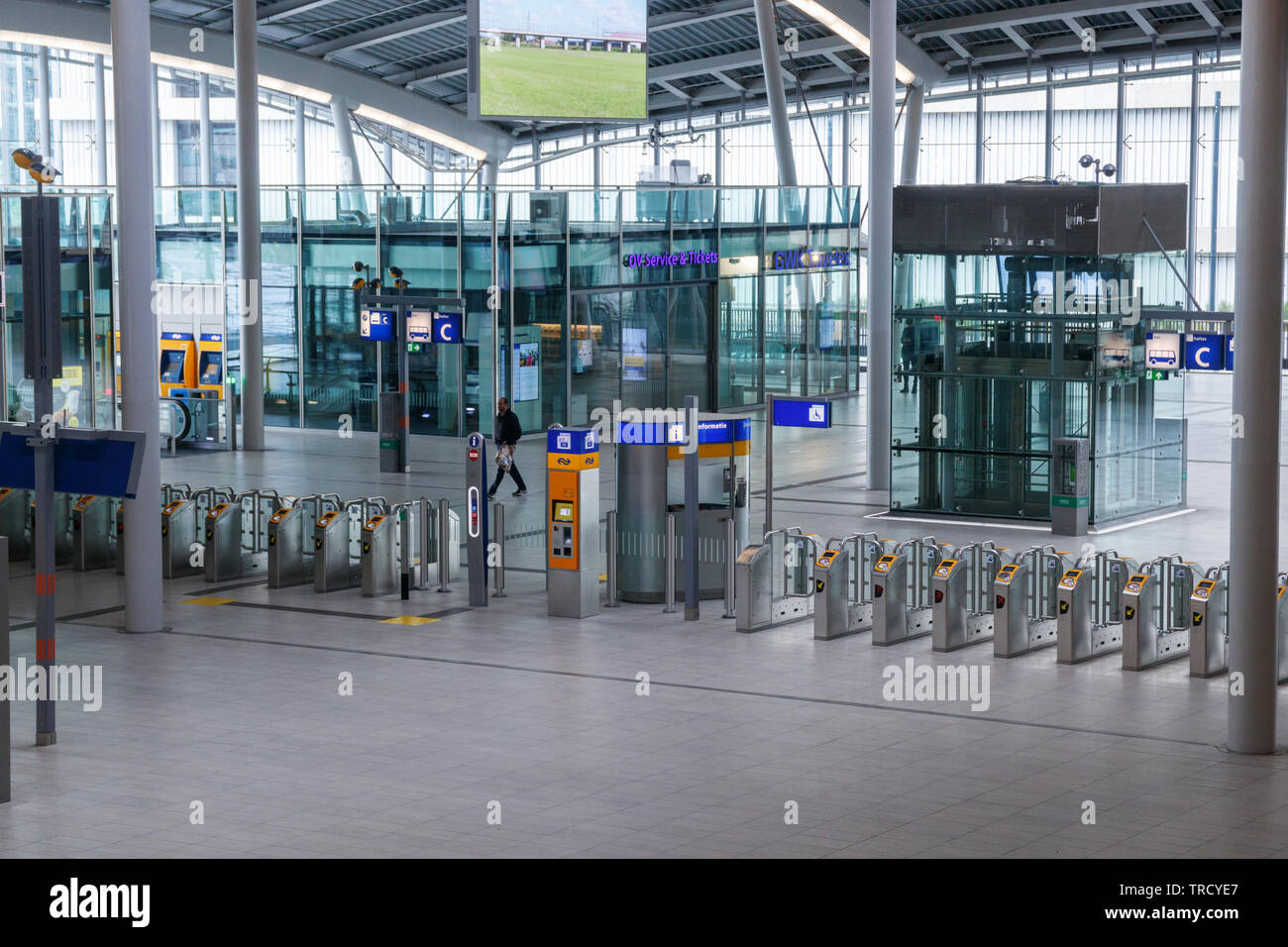 Einsamer Reisender, der zu einer Reihe von Fahrkartensperren in der adesolaten Centraal Bahnhofshalle läuft. Utrechter, Niederlande. Stockfoto