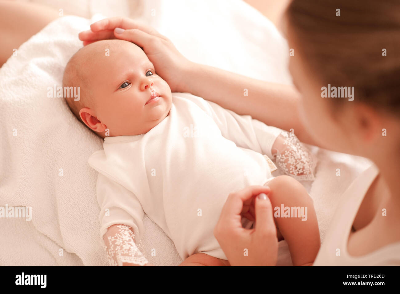 Süße kleine Baby liegend auf Mütter Hände im Zimmer. Mutter und Kind Mädchen an jedem anderen suchen. Die Mutterschaft. Mutterschaft. Stockfoto