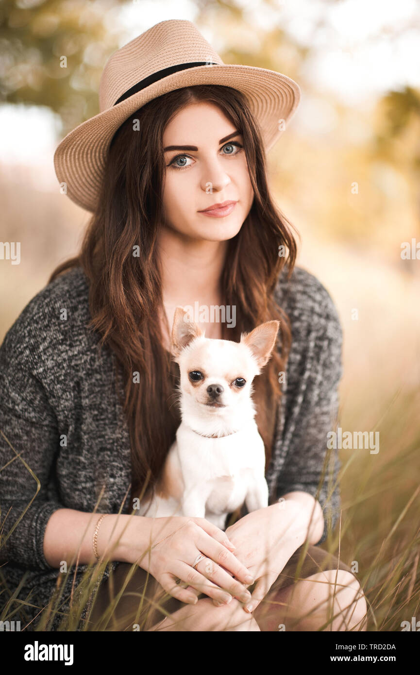 Schöne Mädchen 24-29 Jahre alten Holding chihuahua Welpe in Park. Posing im Freien. Freundschaft. 20. Stockfoto