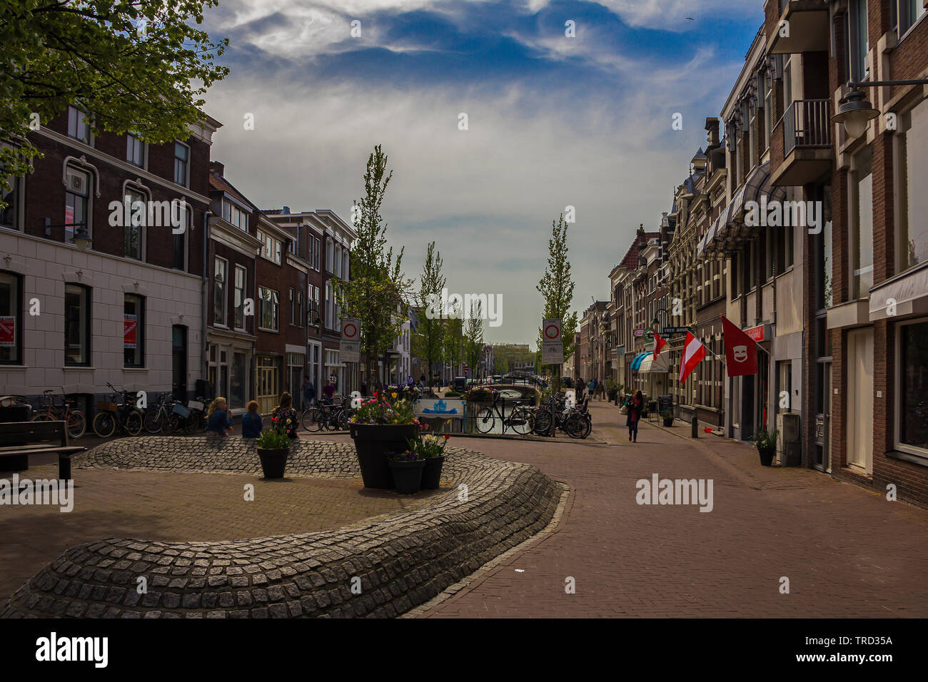 Gouda, Holland, Niederlande, April 23, 2019 ein wenig Platz in Gouda Altstadt, Fahrräder in der Nähe einer Brücke in eine Straße der Stadt geparkt. Blumen auf den hinterg Stockfoto