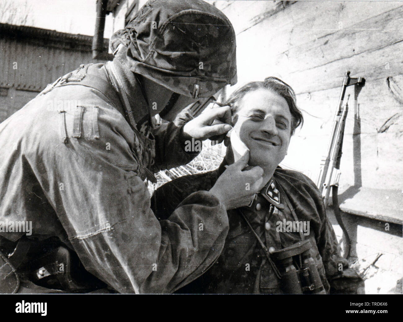 SS-Sturmbannführer Franz Hack hat Gesichtsbehandlung Wunde, die durch Sanitäter behandelt seine MP 44 hinter ist. August 1944 Ostfront PK SS KB Ernst Baumann Stockfoto