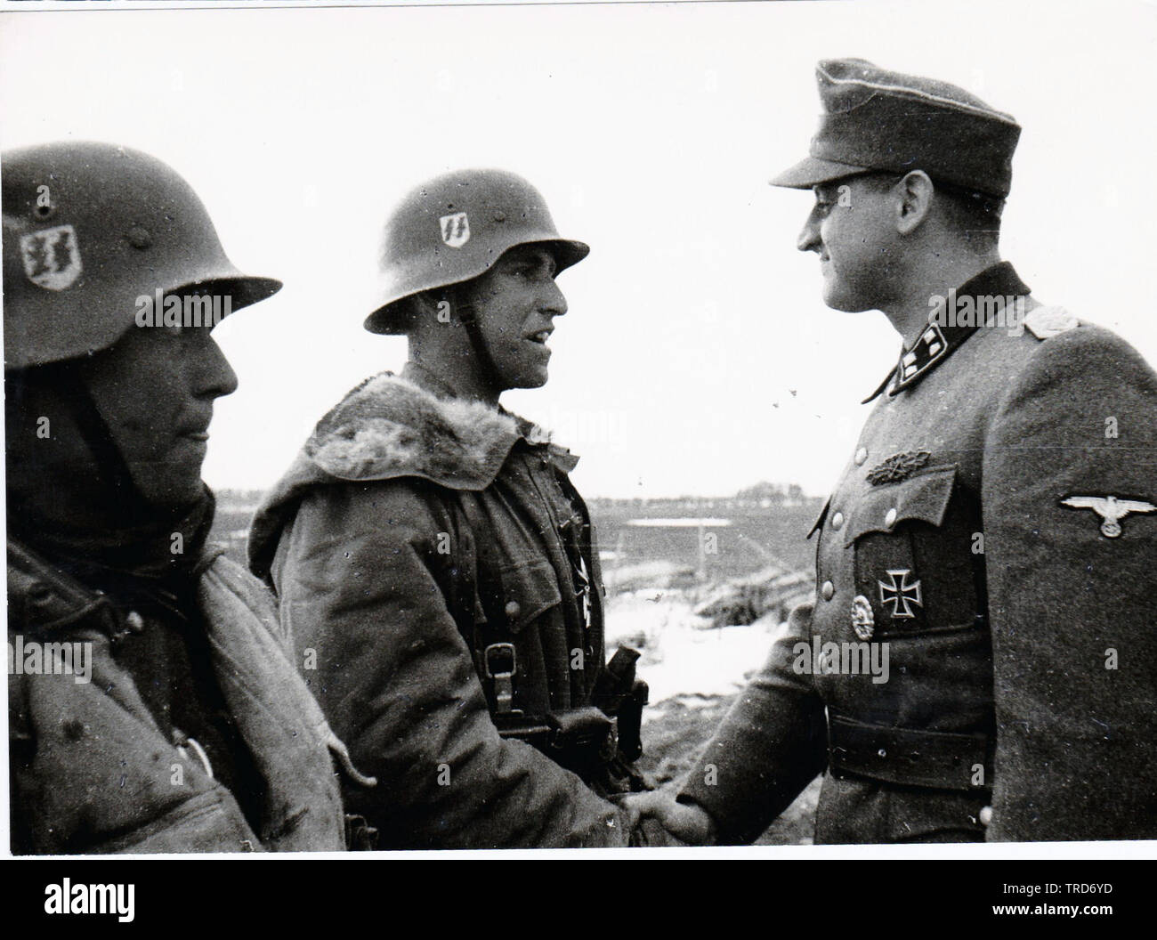 Waffen-SS - Major Sturmbannfuhrer Franz Hack gratuliert zwei seiner Männer im Winter Parkas 1944 an der Ostfront gekleidet Stockfoto