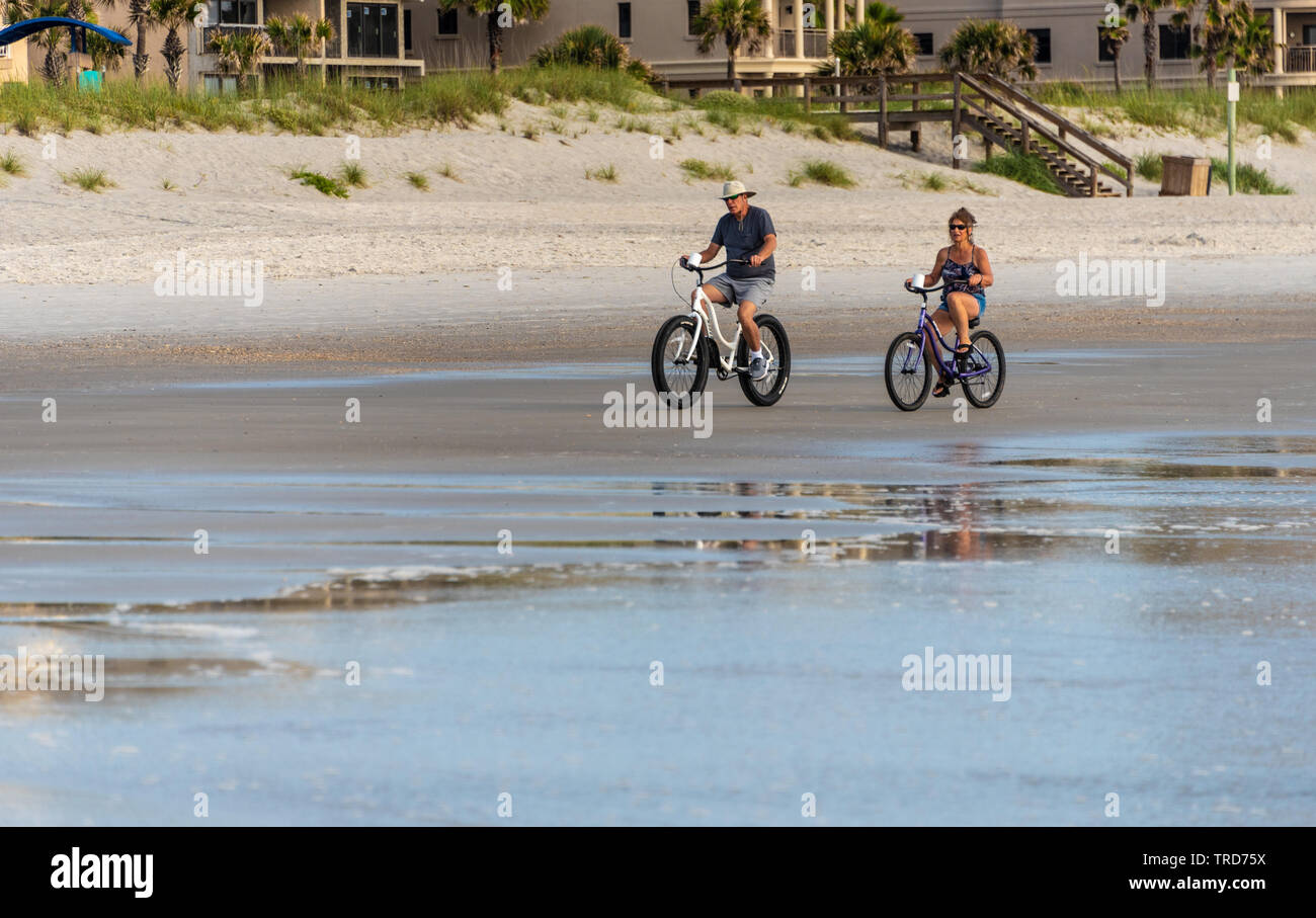 Active Senior Paar reiten Strand Fahrräder bei Sonnenaufgang am Jacksonville Strand im Nordosten von Florida. (USA) Stockfoto