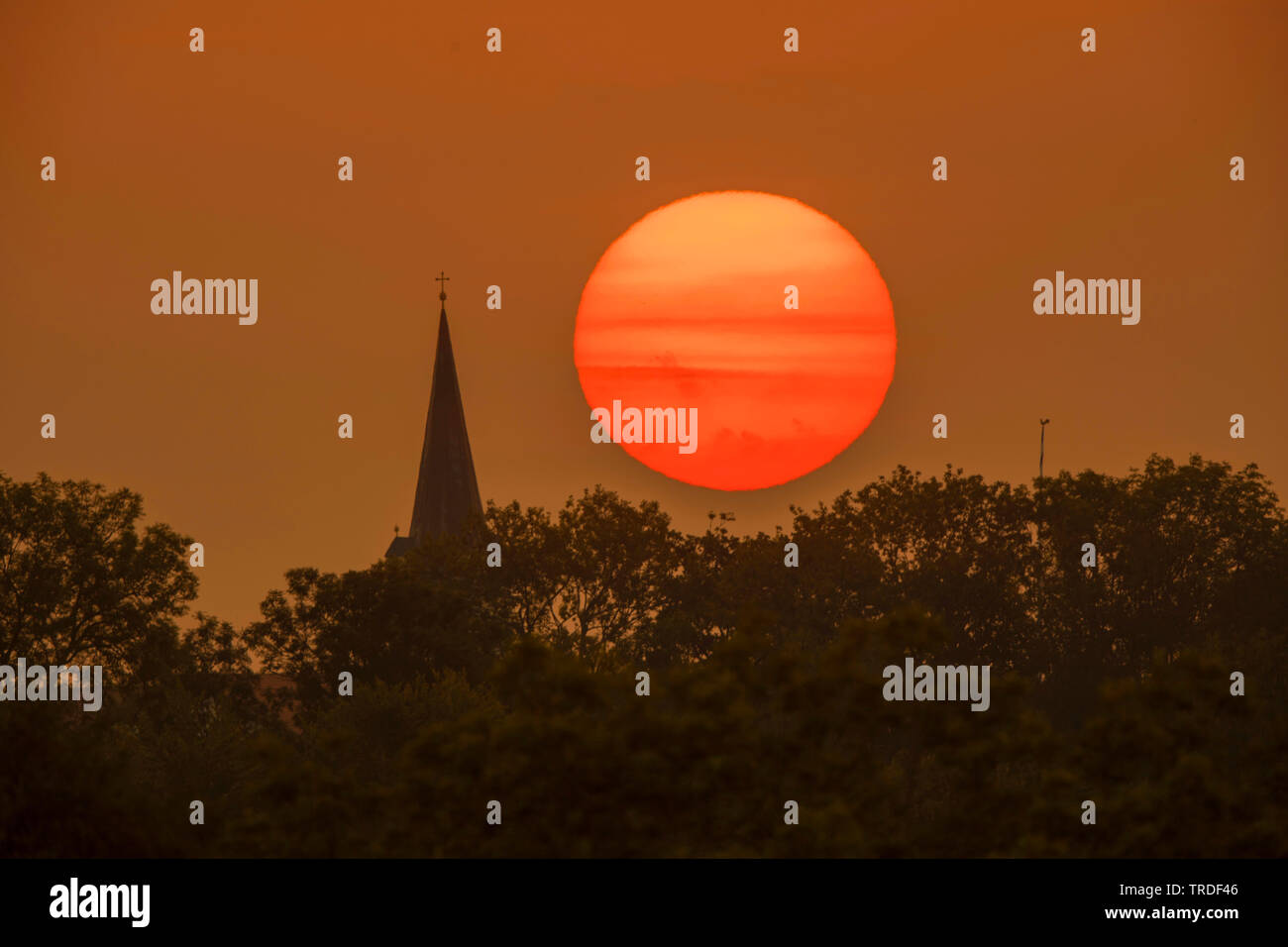 Rote Morgensonne neben Kirchturm, Deutschland, Bayern Stockfoto