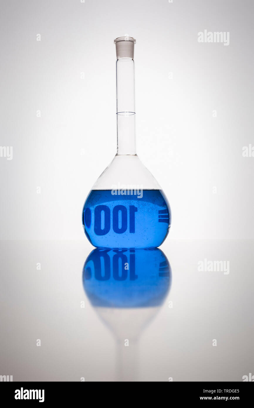Meßkolben mit blauer Flüssigkeit vor weißem Hintergrund gefüllt Stockfoto