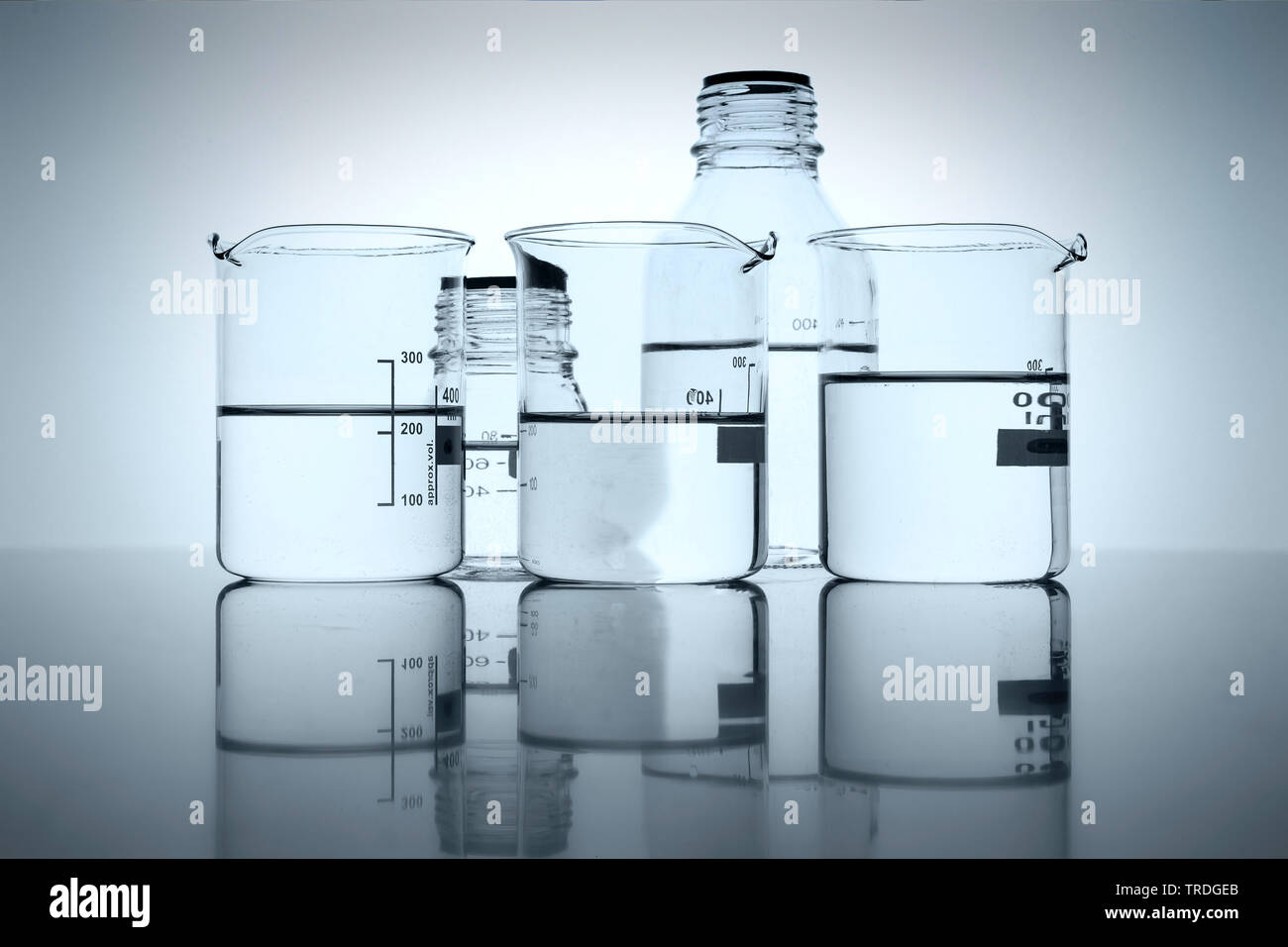 Mehrere verschiedene Flaschen und Becher Gläser mit durchsichtig Flüssigkeiten vor weißem Hintergrund gefüllt Stockfoto