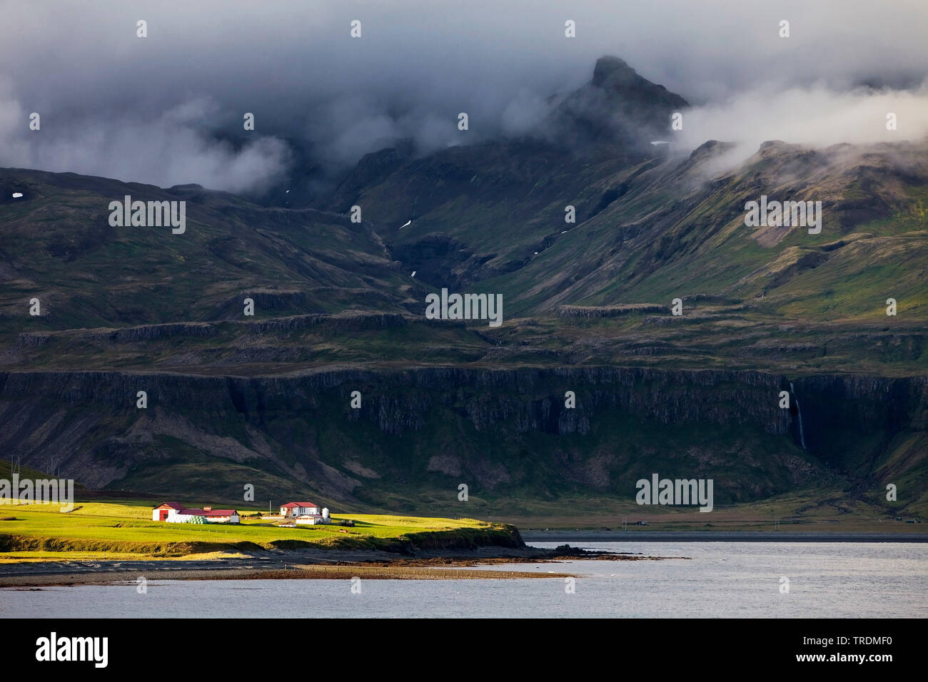 Bauernhaus in der Sonne vor der dunklen Bergwelt, Island, Snaefellsnes, Grindafjoerdur Stockfoto