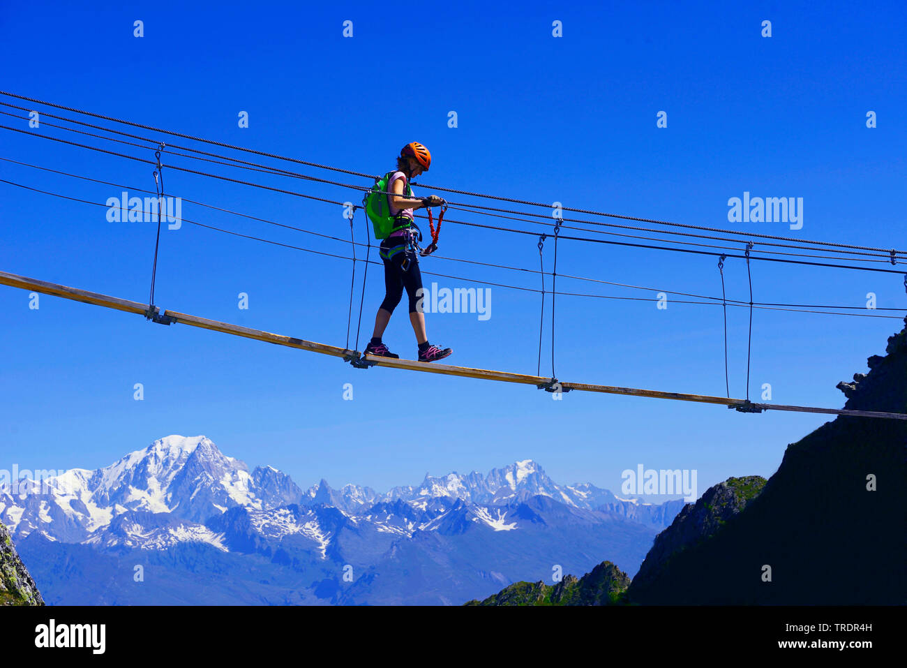 Frau, die über eine einfache Suspension Bridge, Via Ferrata La Plagne, Mont Blanc im Hintergrund, Frankreich, Savoyen, Tarentaise Stockfoto
