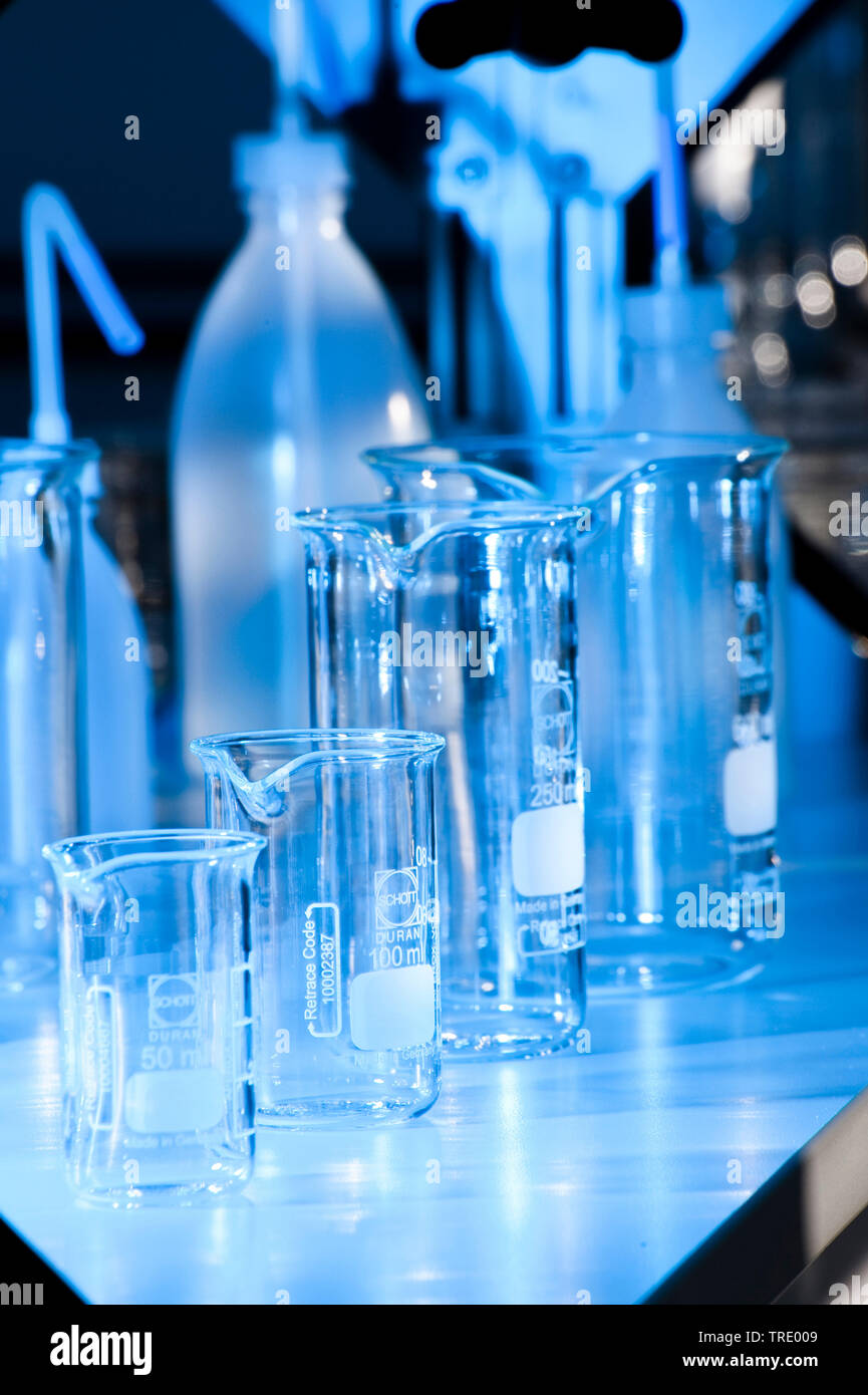 Mehrere verschiedene Flaschen und Gläsern auf einem Labortisch beleuchtet in blaues Licht Stockfoto