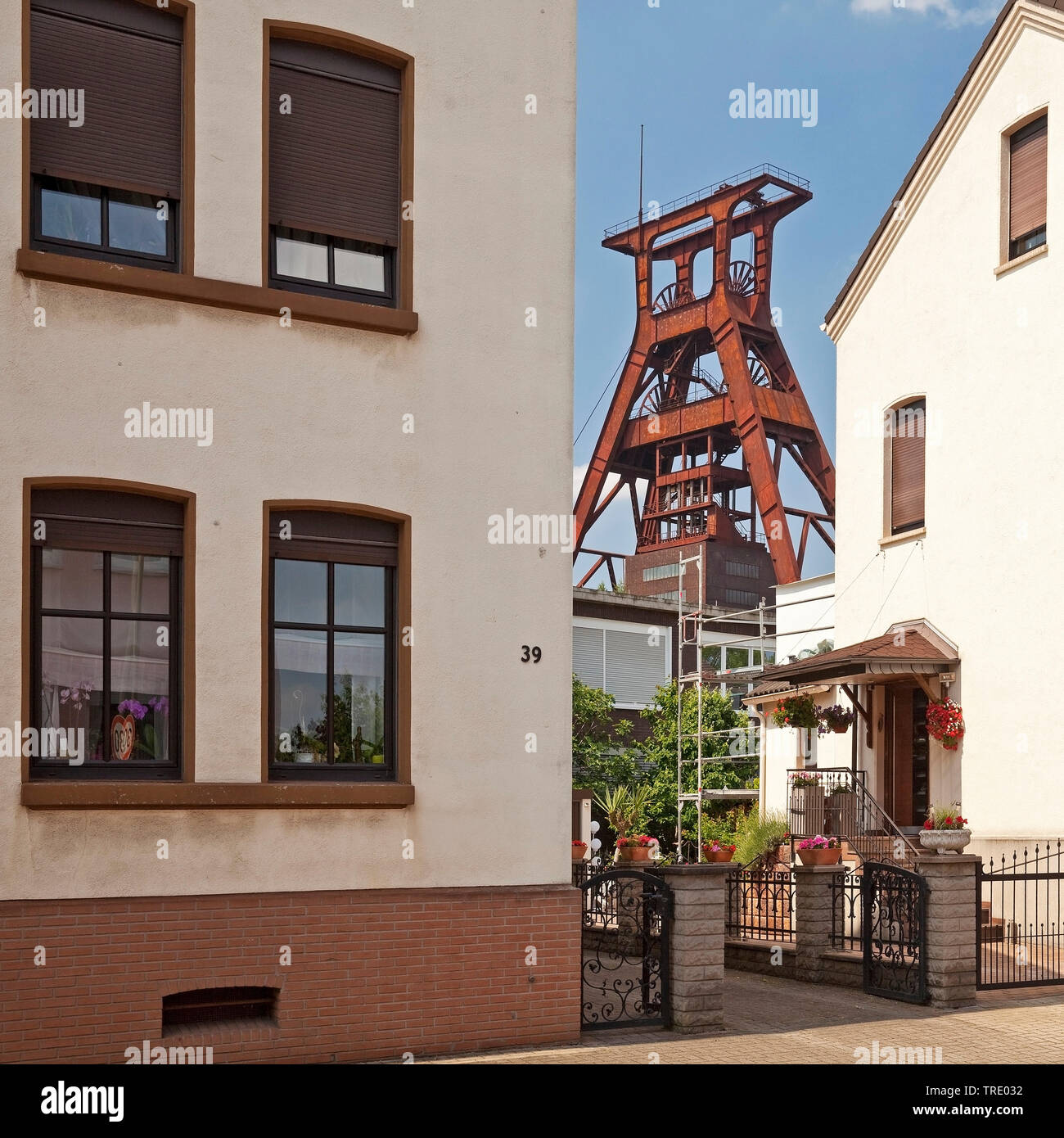 Wohnhäuser mit dem Fördergerüst der Zeche Pluto, Deutschland, Nordrhein-Westfalen, Ruhrgebiet, Herne Stockfoto