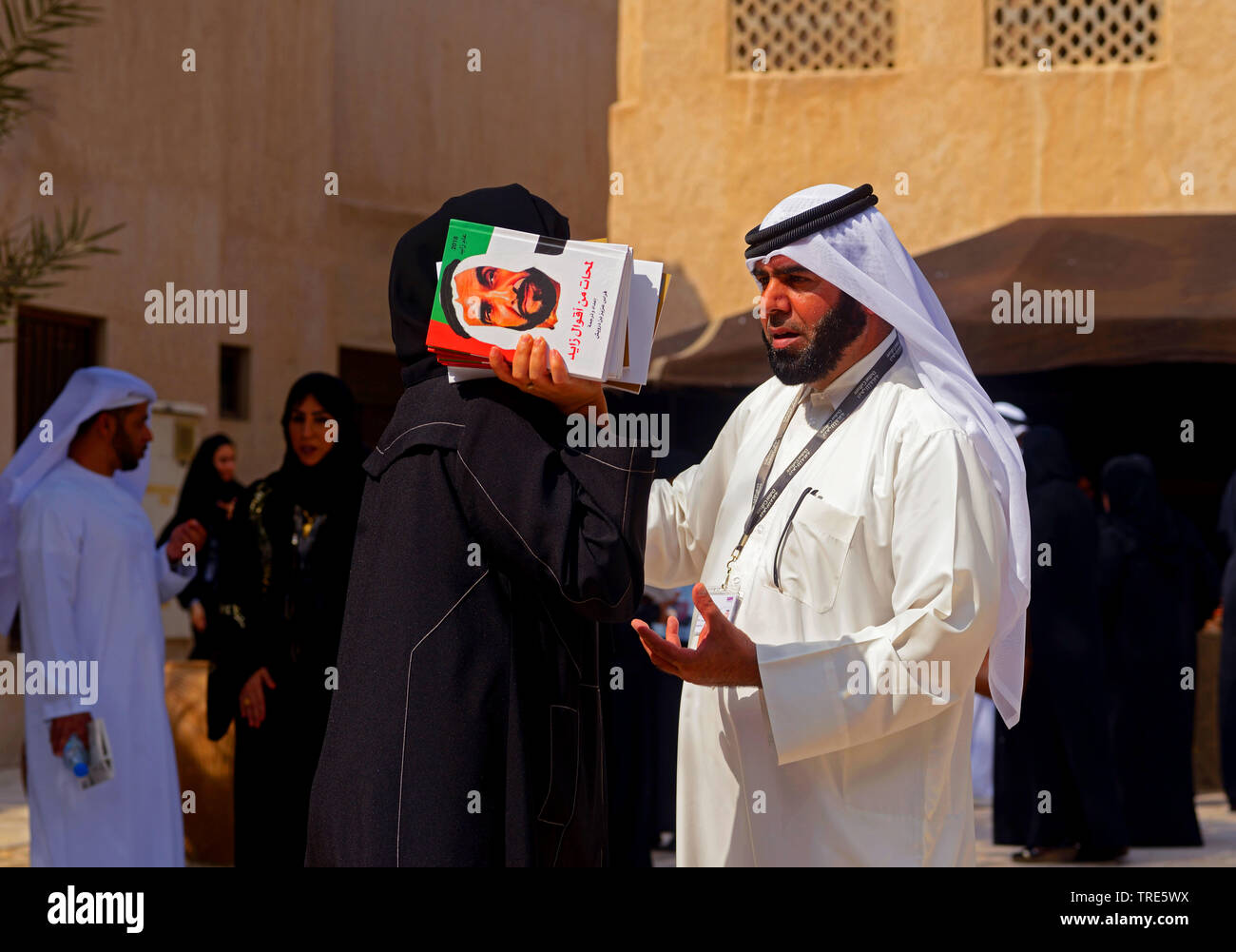 Frau mit Büchern der Seikh Zayed, die die Emirate gebaut. Altstadt von Dubai. Vereinigte Arabische Emirate, Vereinigte Arabische Emirate, Dubai Stockfoto