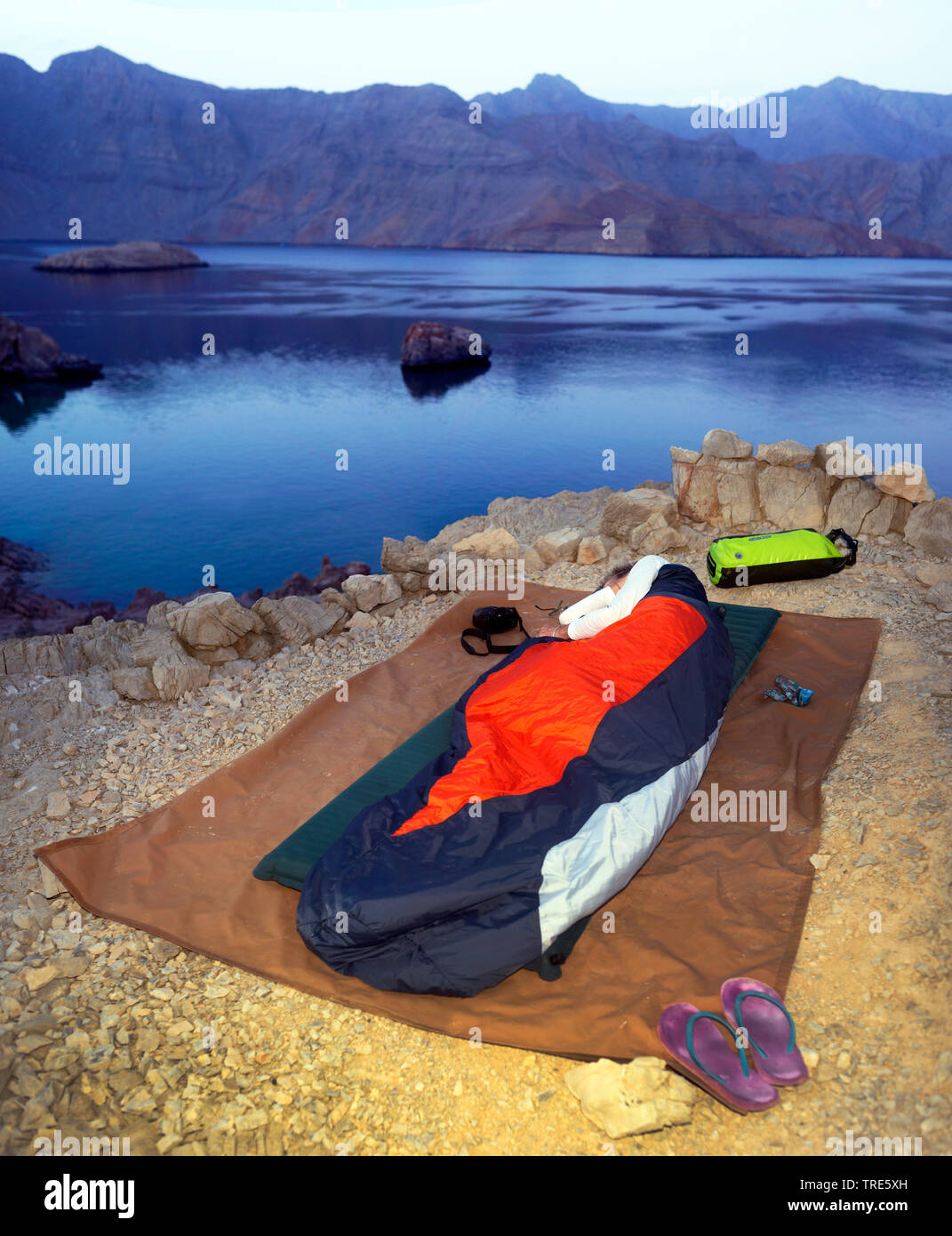 Frau verbringen die Nacht im Freien auf der felsigen Küste der Straße von Hormuz, Oman, Shamamar, Khasab Stockfoto