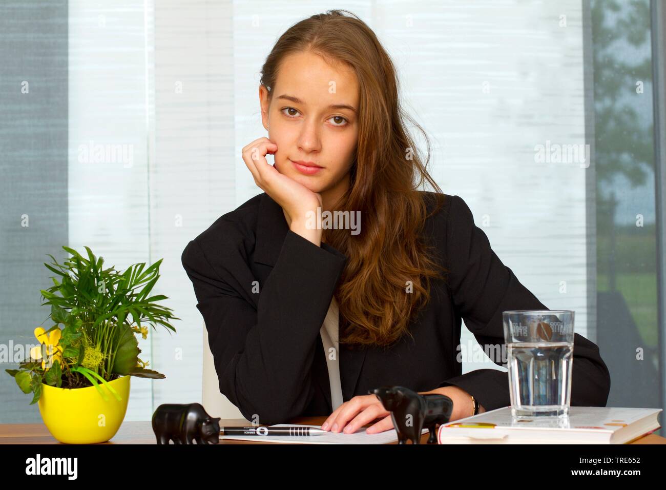 Porträt einer jungen Frau am Schreibtisch sitzen und schauen in die Kamera Stockfoto