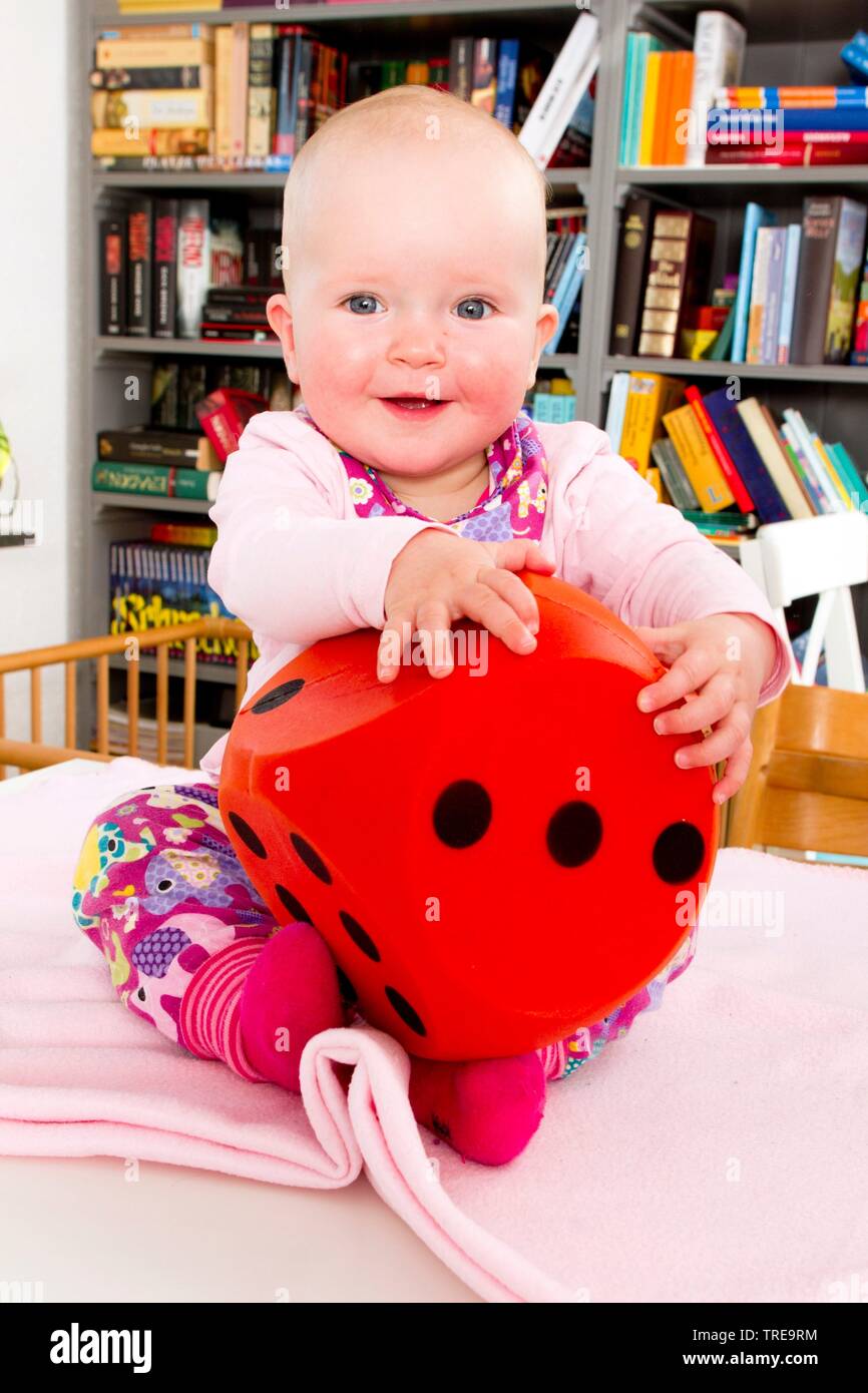 Babysitting in einem Kinder ┤ s Bett mit einem überdimensionalen Würfel in seinen Händen Stockfoto