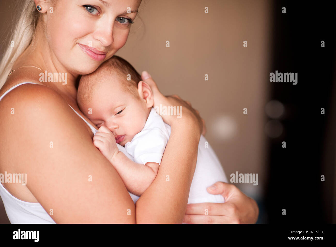 Happy Mother Holding Baby im Zimmer Nahaufnahme. Die Mutterschaft. Mutterschaft. Stockfoto