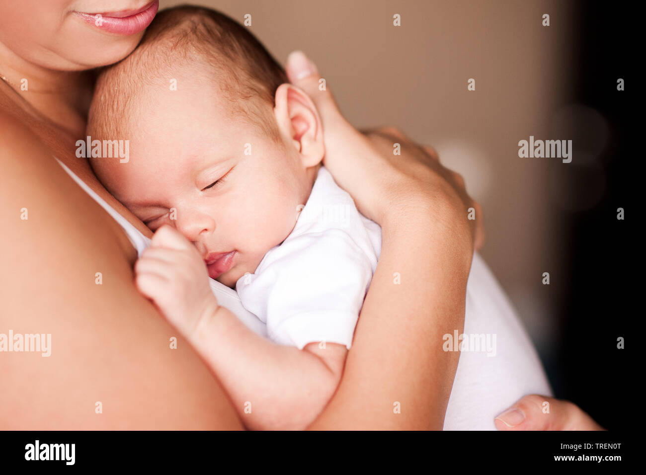 Lächelnde Mutter Holding Baby auf Händen hautnah. Die Mutterschaft. Mutterschaft. Schlafende Kind. Stockfoto