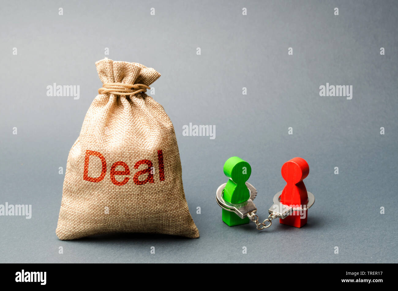 Es sind zwei Personen miteinander in Handschellen und neben den Beutel mit der Aufschrift Abkommen stehen. Nicht geschlossene Verpflichtungen zwischen zwei Personen, finanzielle oder moralische Schuld. Ref. Stockfoto