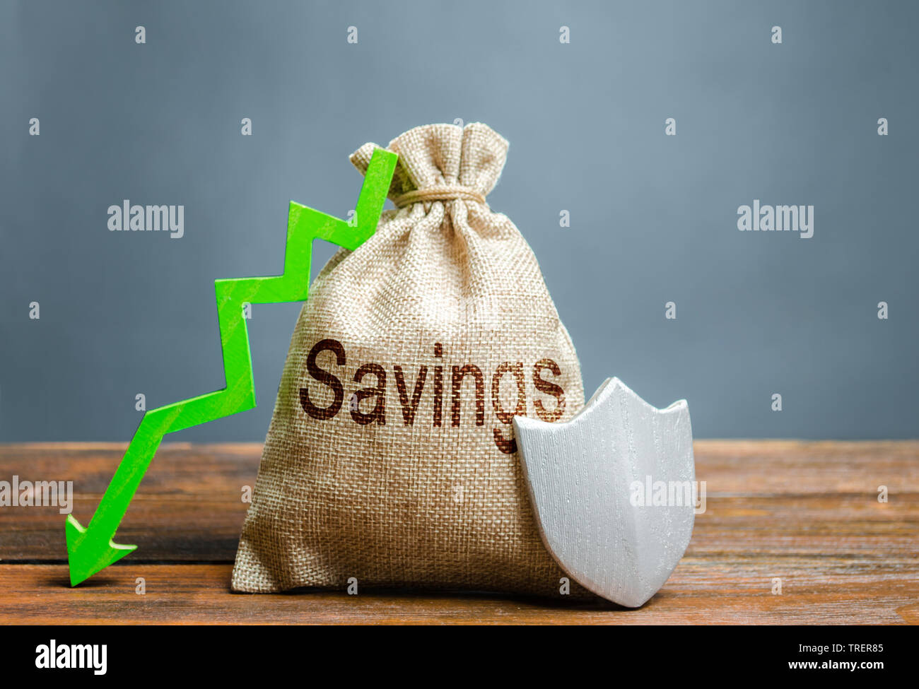 Beutel mit der Aufschrift Einsparungen, Schild und grünen Pfeil nach unten. Garantierte Schutz der persönlichen Ersparnisse, Investitionen. Schutz von Geschäfts- und Capi Stockfoto