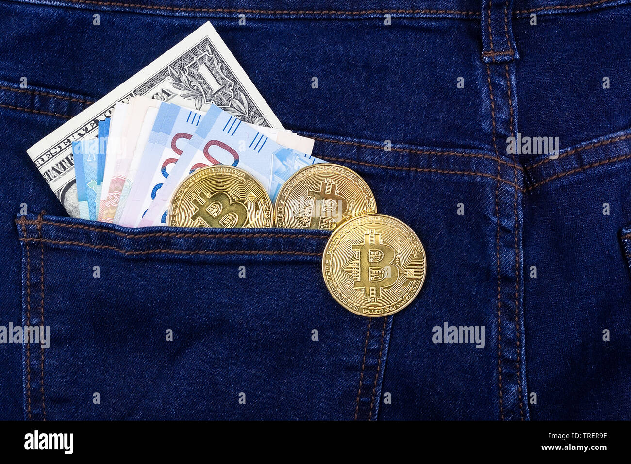 Bitcoin cryptocurrency in die Tasche blaue Jeans und Dollar Banknoten, Rubel Stockfoto