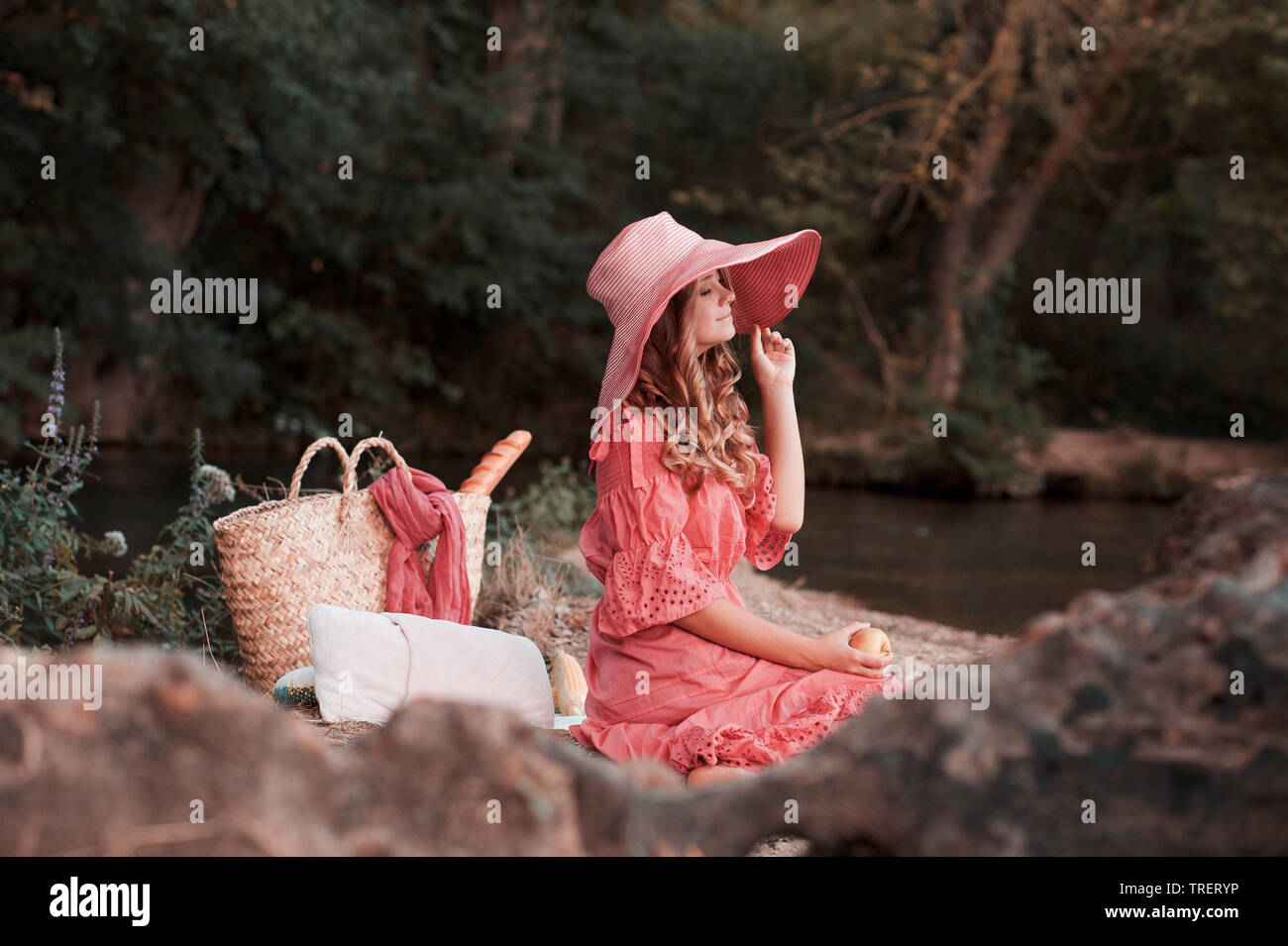 Lächelnde Mädchen tragen stilvolle rosa kleid und hut. Das Picknick im Freien. 20. Stockfoto