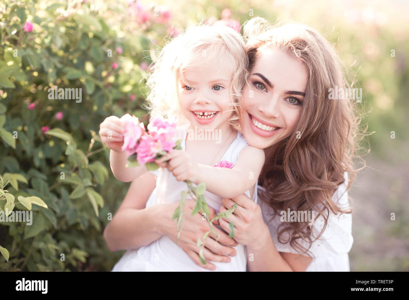 Lächelnde Mutter Holding Baby Mädchen 4-5 Jahre alten lachen draußen in der Wiese. Mit Blick auf die Kamera. Die Mutterschaft. Kindheit. Stockfoto
