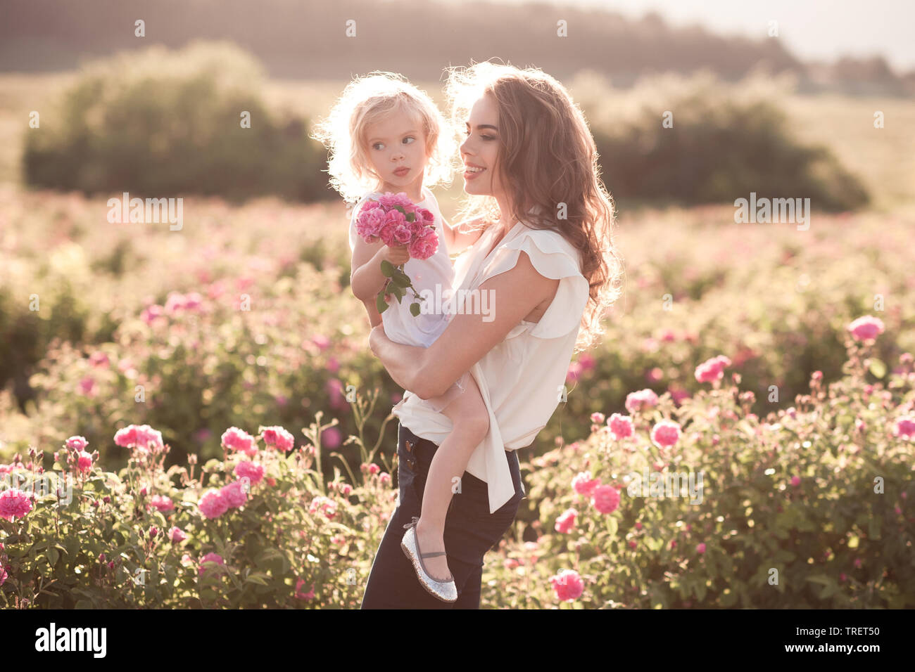Frau mit Baby 3-4 Jahr alt in Rose Feld. Sommer Saison. Die Mutterschaft. Zeit mit der Familie. Stockfoto