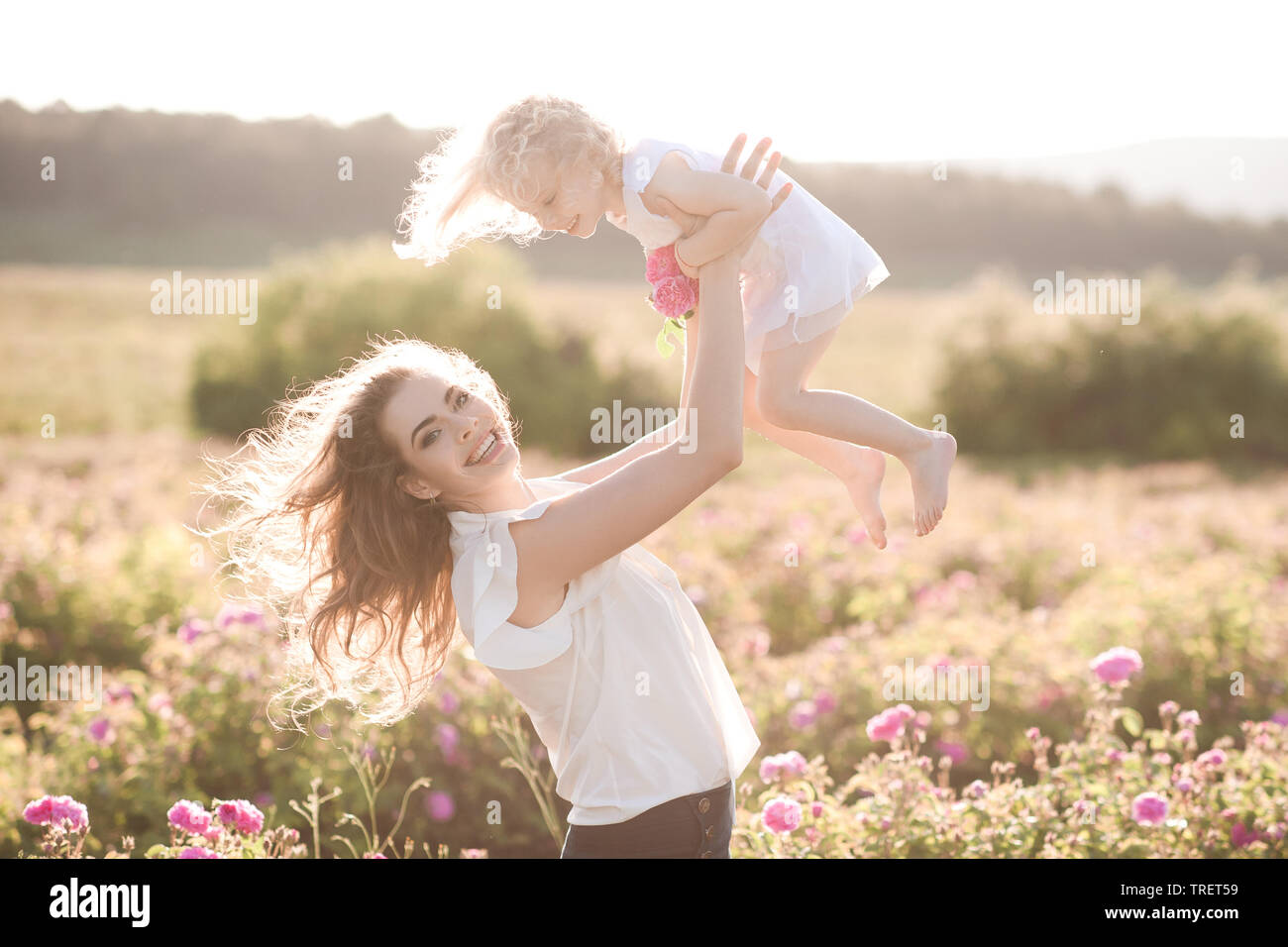Glückliche Mutter spielt mit Kind Tochter im Freien. Mit Blick auf die Kamera. Die Mutterschaft. Glück. Stockfoto