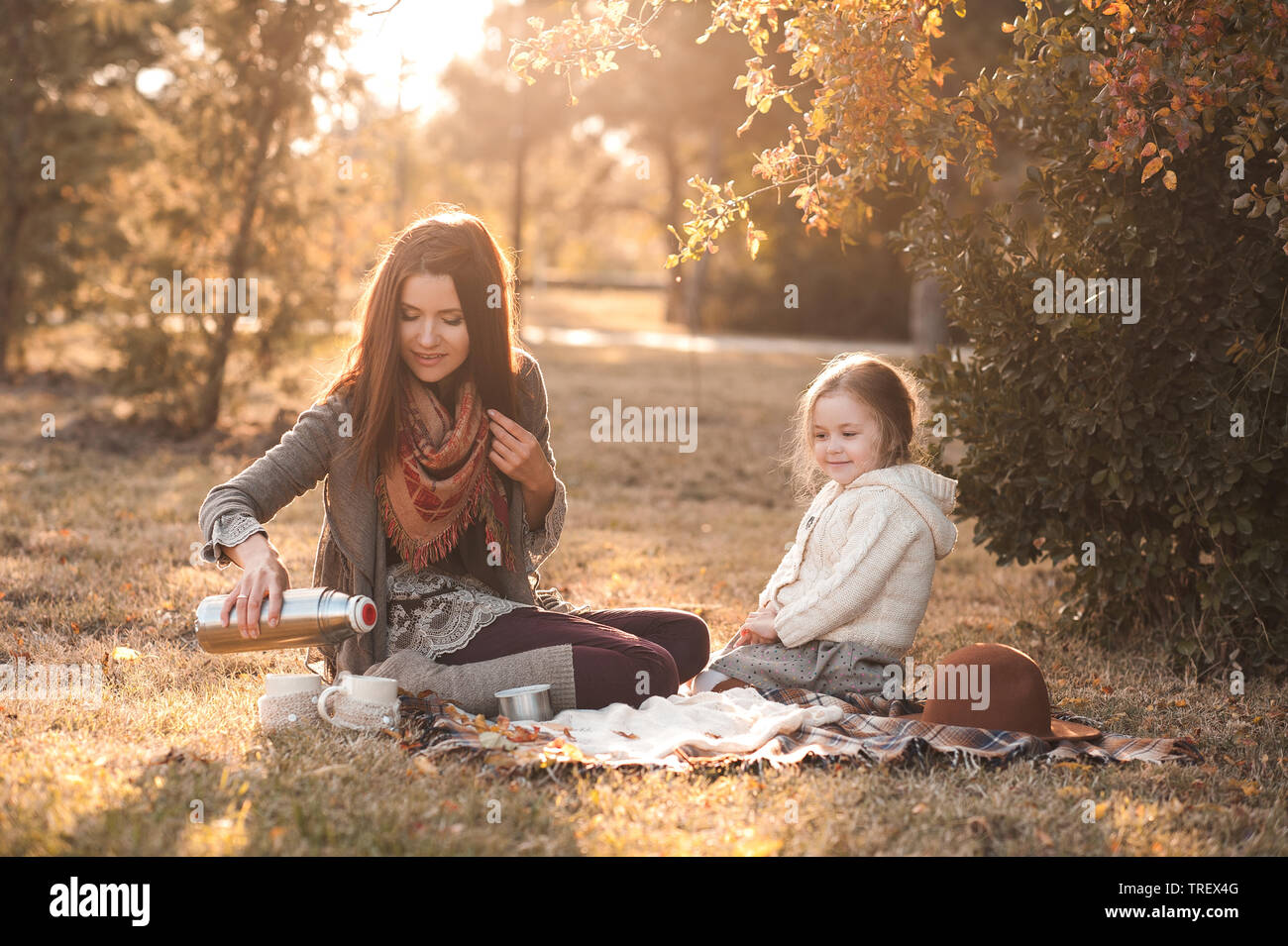 Lächelnde Mutter 20-24 Jahre alten Kind und Tochter 4-5 Jahr alt haben Picknick mit heißem Tee im Freien. Die Mutterschaft. Zeit mit der Familie. Stockfoto