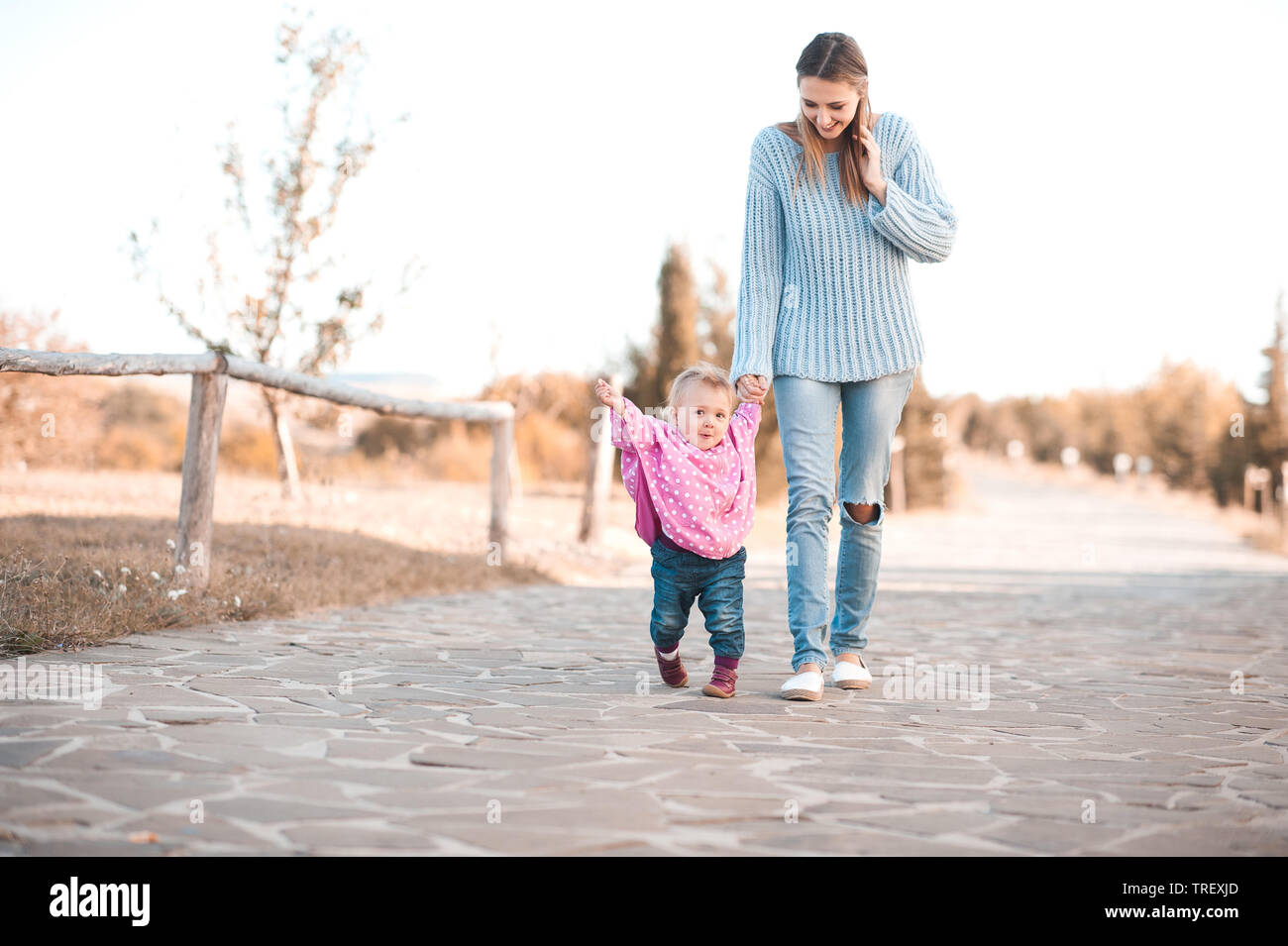 Baby girl 1 Jahr alt, erste Schritte halten Mütter hand Walking im Park. Legere Kleidung Herbst im Freien. Die Mutterschaft. Stockfoto