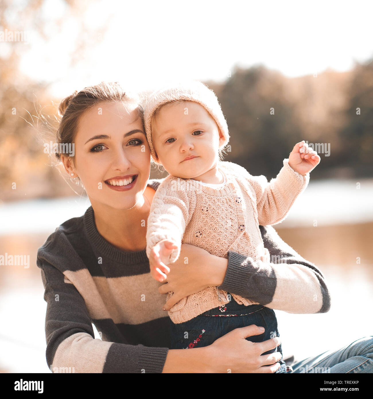 Lächelnde Mutter Holding baby girl 1 Jahr alt tragen aus Gewirken Kleider posiert im Freien. Mit Blick auf die Kamera. Die Mutterschaft. Stockfoto