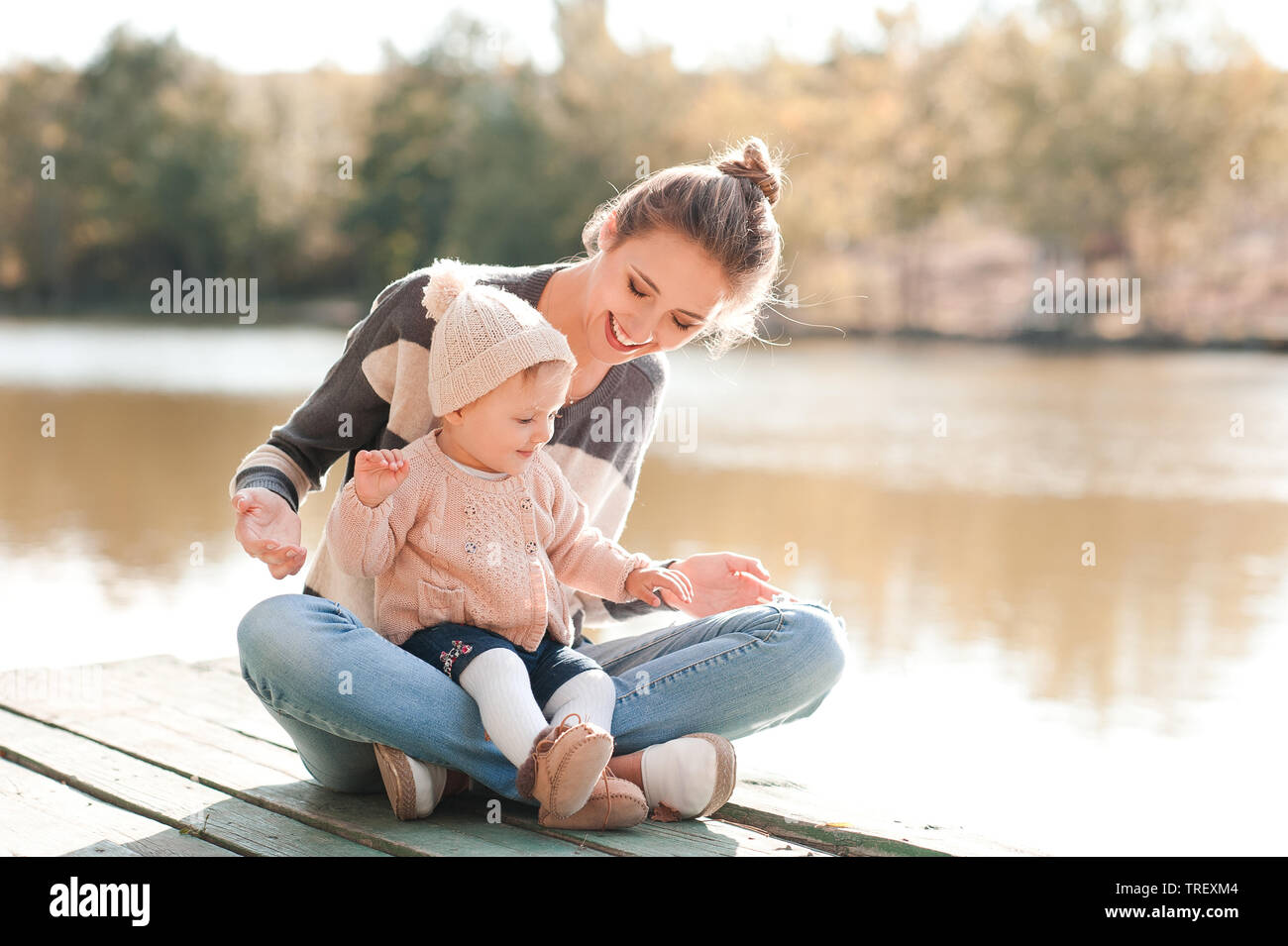 Lächelnde junge Mutter mit Baby girl 1 Jahr alt legere aus Gewirken Kleider im Freien. Die Mutterschaft. Stockfoto